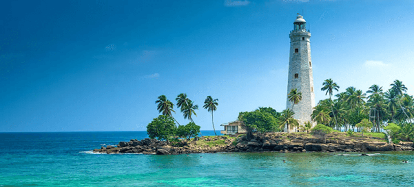 White lighthouse on a tropical rocky coast in Sri Lanka